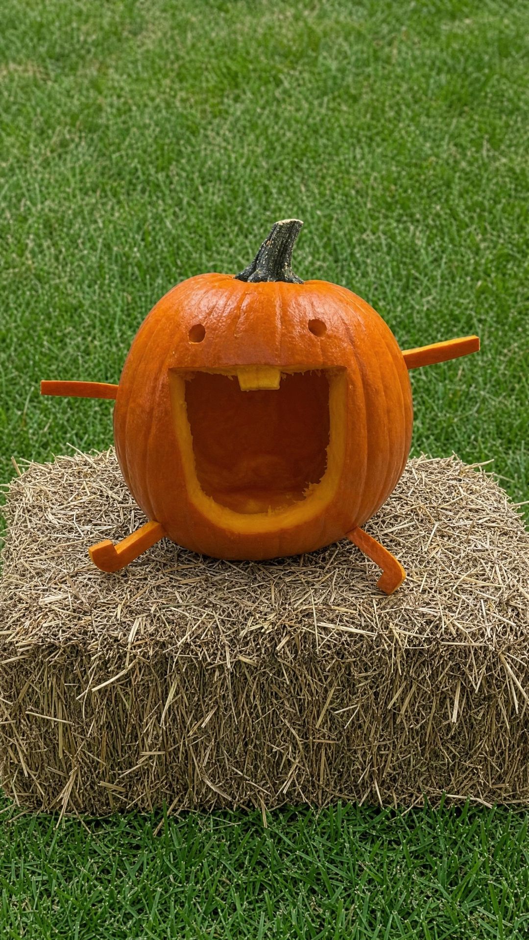 Cheerful carved pumpkin sitting on a hay bale